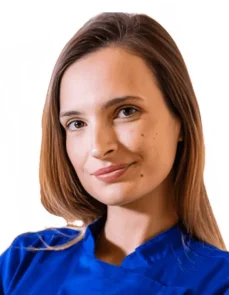 La Dott.ssa Roberta Carlini Coppedè è ritratta con capelli lisci e castani, indossa un top blu royal e sorride dolcemente. Ha un segno di bellezza sulla guancia ed è in posa su un semplice sfondo bianco presso il Medical Hub di Roma.